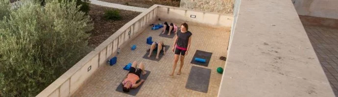 Pilates and teacher with Pilates guest on outside terrace in Sicily