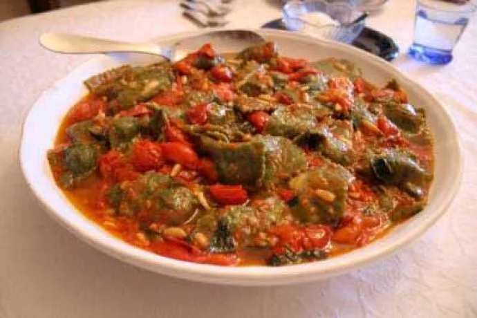 Spinach pasta with tomato on pine nuts