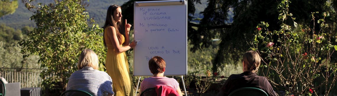Italian language teacher with students writing on white board in Tuscany