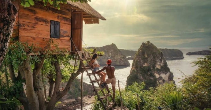 couple looking at seaside view while staying at a treehouse