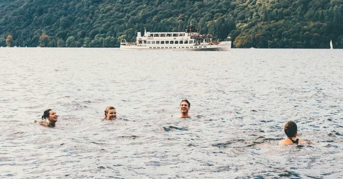 group of adults doing wild swimming in a lake