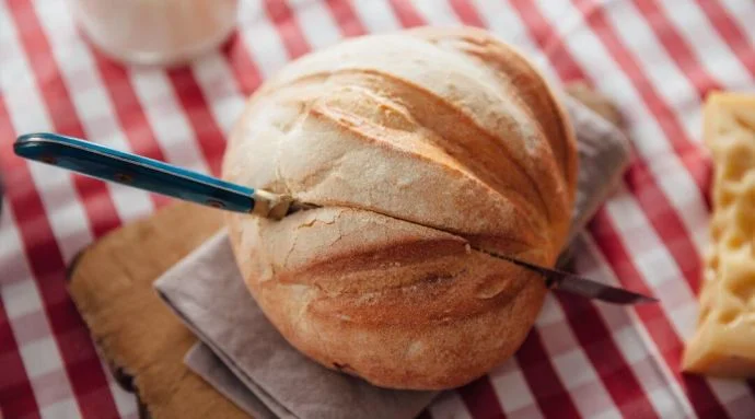 A knife placed within a loaf of bread